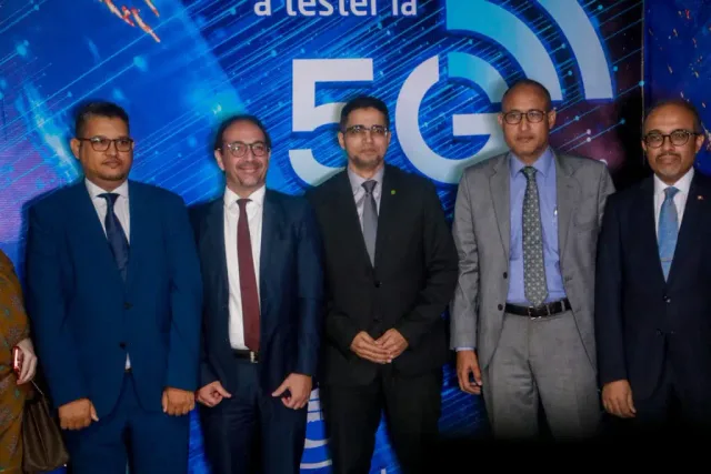 مسؤولون يقفون أمام لافتة لاختبار شبكة الجيل الخامس