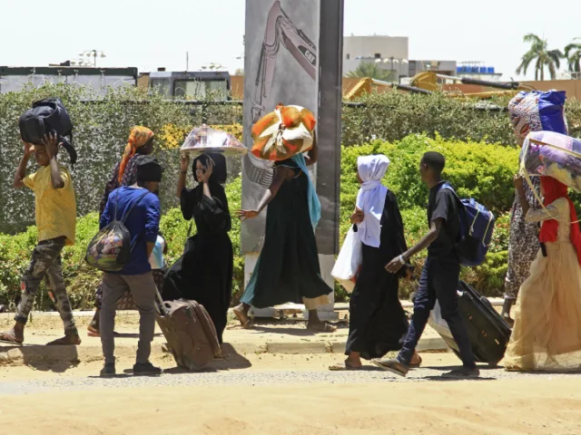رجال ونساء وأطفال سودانيون يسيرون على جانب طريق حاملين حقائب وأمتعة على رؤوسهم، صورة أرشيفية