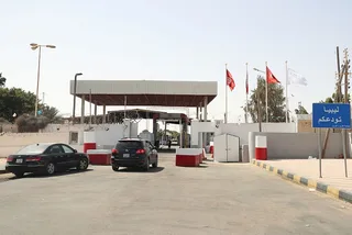 مدخل معبر حدودي بري بين تونس وليبيا تظهر فيه سيارات ولافتة كتب عليها ليبيا تودعكم، صورة أرشيفية