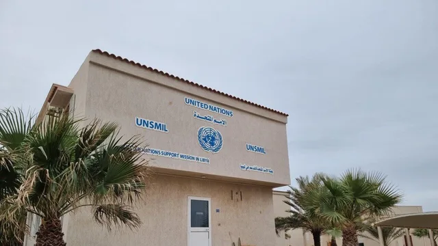 مبنى يحمل شعار الأمم المتحدة واسم بعثتها للدعم في ليبيا تحيط به أشجار نخيل، صورة أرشيفية
