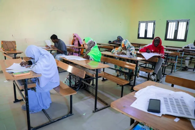 تلاميذ يجلسون إلى طاولات في قاعة امتحان ويكتبون على أوراق
