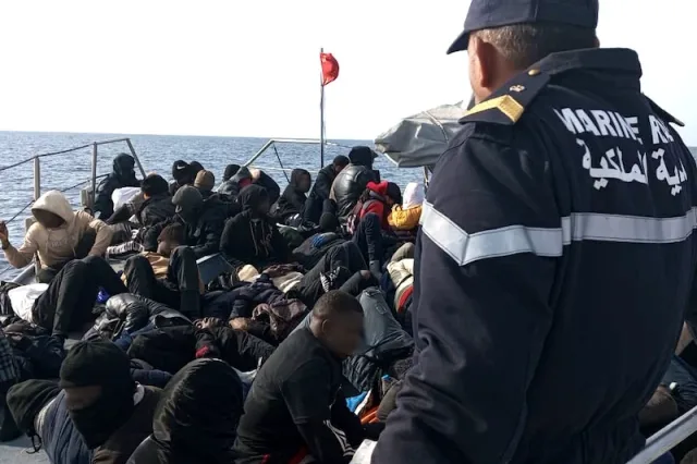 عنصر من البحرية الملكية المغربية قرب مجموعة من المهاجرين على متن زورق في البحر، صورة أرشيفية