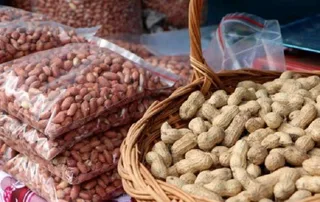 سلة من الخيزران مليئة بالفول السوداني بقشره وبجانبها أكياس من الفول المقشر، صورة تعبيرية من الأرشيف