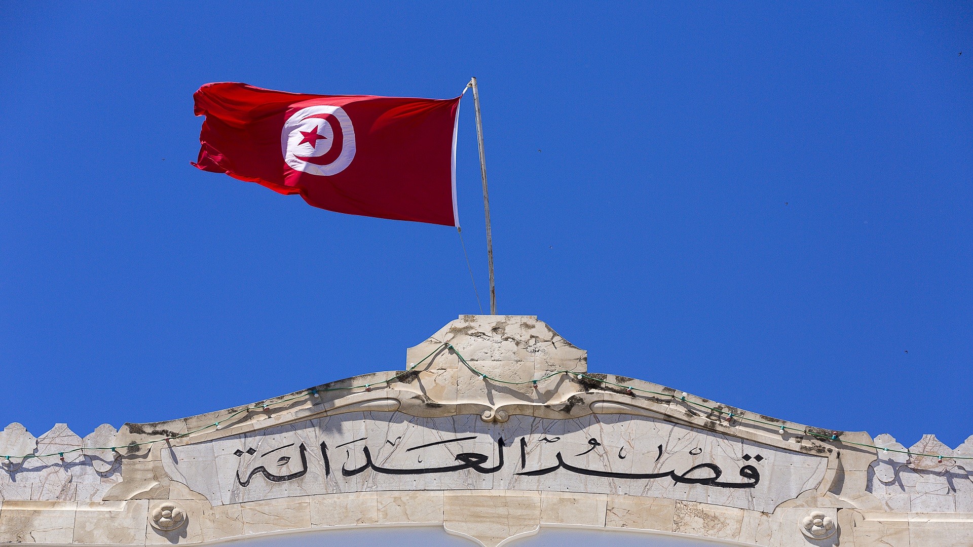 علم تونس يرفرف فوق واجهة حجرية كتب عليها "قصر العدالة"، صورة أرشيفية