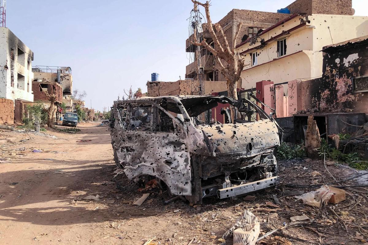 هيكل مركبة محترقة ومثقوبة بالرصاص في شارع متضرر بالحرب في السودان، صورة أرشيفية