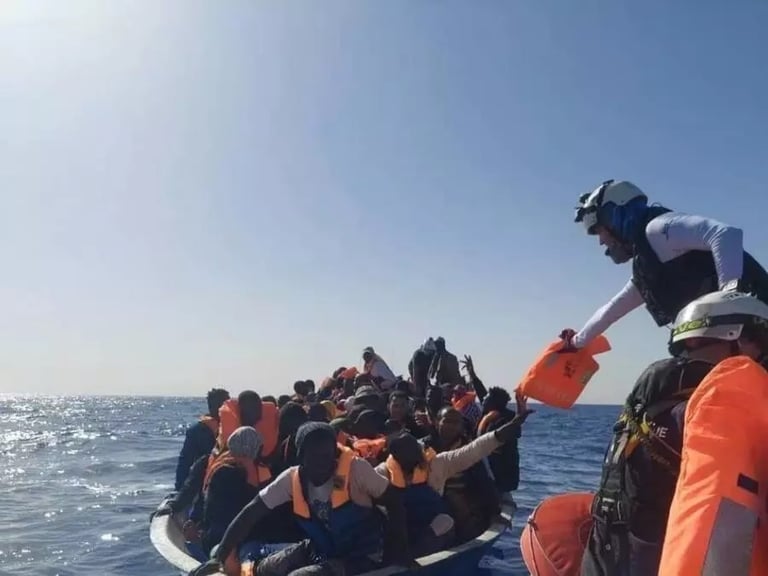 منقذون يسلمون سترات نجاة لمهاجرين على متن قارب مكتظ في عرض البحر