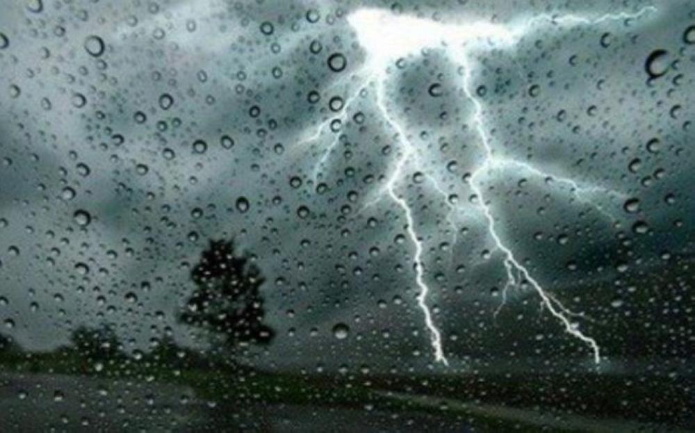 برق في سماء ملبدة بالغيوم خلف زجاج تغطيه قطرات المطر، صورة توضيحية
