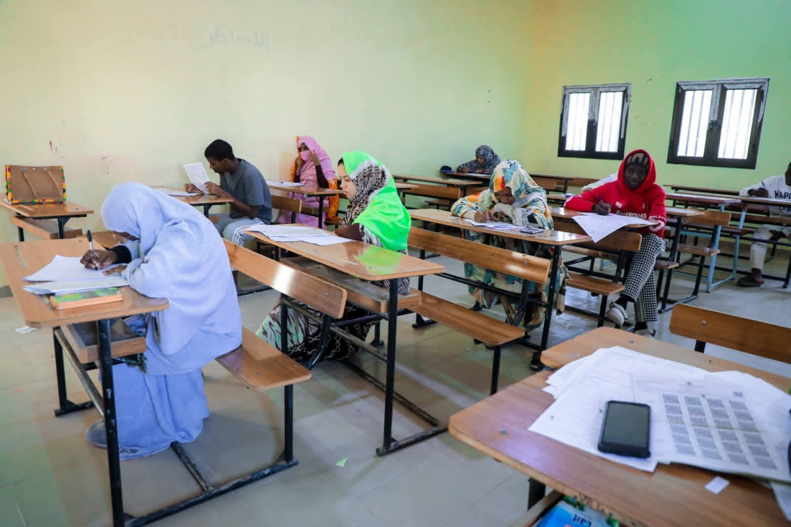 تلاميذ يكتبون على طاولات داخل قاعة دراسية
